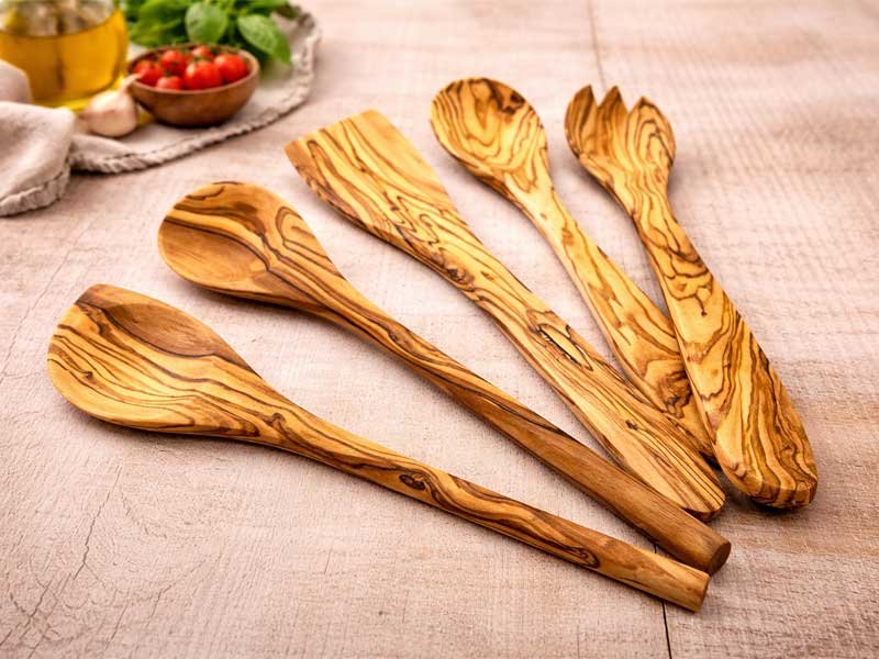 Olivenholz Kochlöffel Set mit verschiedenen Küchenutensilien auf Holzuntergrund